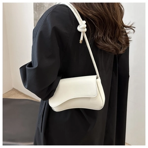 Détail du sac bandoulière en similicuir crème avec rabat vague et sangle nouée