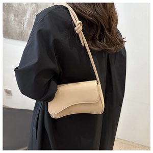 Detail of beige minimalist leather bag with unique knotted strap shown on model shoulder
