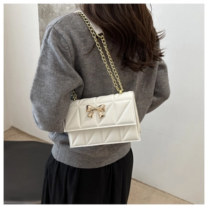Détail du sac à bandoulière blanc matelassé avec fermoir papillon doré et chaîne