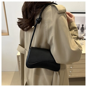 Close-up of black half-moon shoulder bag with knotted strap and gold metal accents