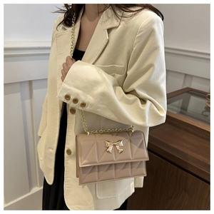 Détail du sac à bandoulière matelassé beige avec fermoir papillon doré sur modèle