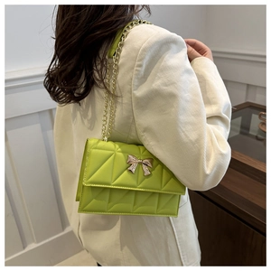 Détail du sac bandoulière matelassé vert fluo avec boucle papillon dorée et chaîne