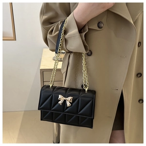 Gros plan sur le sac matelassé noir avec boucle papillon dorée et bandoulière chaîne