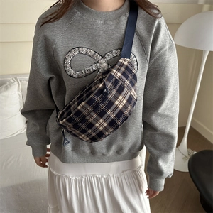 Fashionable checkered crossbody bag in blue and white canvas worn by female model