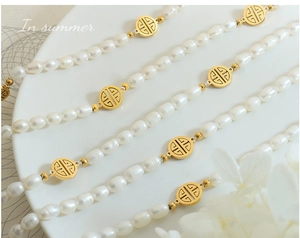 Nahaufnahme der Perlenkette mit goldenem Fu-Anhänger auf einem eleganten weißen Tablett