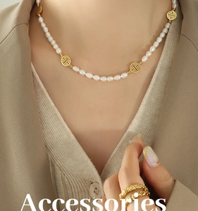 Details einer Süßwasserperlenkette mit goldenen Glücksbringern und Ringen