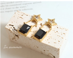 Vue détaillée de boucles d'oreilles cristal noir avec clous étoile dorée sur pierre