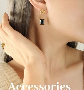 Gros plan de boucles d'oreilles étoile dorées avec cristaux noirs portées par un mannequin