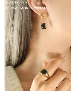 Détail de boucles d'oreilles étoile avec gemme noire et bague dorée assortie