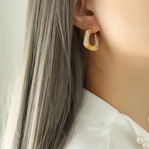 Gold U-shaped pearl earrings with ribbed texture on model for a slimming face look