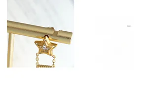 Détail de la boucle d'oreille étoile dorée avec cristal central et texture métallique