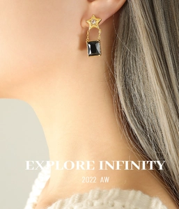 Détail de puce d'oreille étoile avec pendentif en pierre noire et chaîne dorée sur mannequin