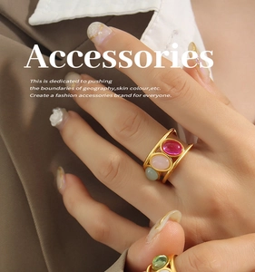Close-up of gold chunky rings with red, pink and green oval gemstones on model hand