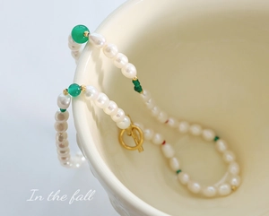 Détail d'un collier de perles d'eau douce avec agate verte et fermoir OT doré sur tasse