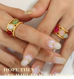 Close-up of vintage gold geometric rings featuring colorful oval cabochon gemstones