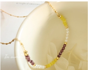 Détail d'un collier de perles avec pierres œil-de-chat jaunes et violettes et perles