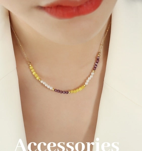 Détail du collier choker avec perles œil-de-chat jaunes et violettes sur une chaîne dorée