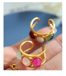 Close-up of gold-plated rings featuring colorful resin gemstones on hand model
