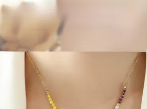 Gros plan d'un collier de perles en œil de chat jaune et violet porté par un mannequin