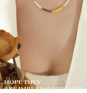Détail d'un collier ras du cou perlé avec pierres œil de chat jaunes et violettes sur mannequin