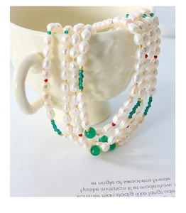 Détail d'un collier de perles baroques multicouche avec accents de perles rouges et vertes