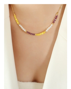 Détail du collier de perles en œil de chat jaune et violet sur le cou d'un mannequin