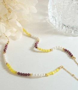 Détail du collier de perles avec pierres œil de chat et chaîne dorée
