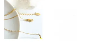 Détail du collier de perles dorées 18K avec fermoir mousqueton et chaîne d'extension