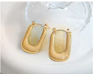 Gros plan détaillé de boucles d'oreilles dorées en U avec une texture élégante et nervurée