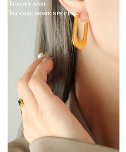 Gros plan de boucles d'oreilles en U dorées brossées et bague en pierre verte