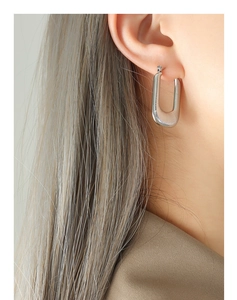 Détail de boucles d'oreilles en U dorées avec texture linéaire sur l'oreille d'un mannequin