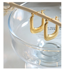 Gros plan de boucles d'oreilles en U plaquées or 18 carats avec texture métal brossé