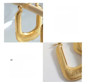 Détail macro des boucles d'oreilles en acier titane doré en U avec rayures texturées