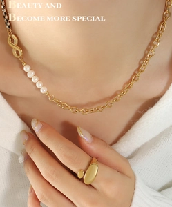 Detail of gold necklace with infinity link and freshwater pearls worn by model