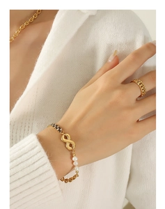 Detailed view of a gold infinity bracelet featuring black zircon and freshwater pearls