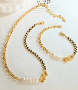 Detailed view of gold infinity jewelry set with white pearls and checkered pattern inlay
