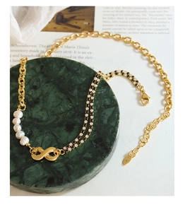 Detail of infinity pendant necklace featuring pearls and pavé cubic zirconia on gold chain