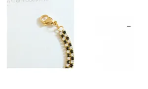 Macro detail of 18K gold checkerboard bracelet with lobster clasp and engraved tag