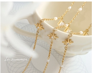 Dettaglio della collana con pendente a stella dorata con perla e pietre di zirconia