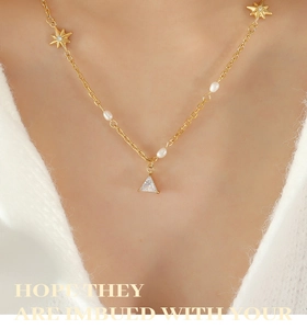 Dettaglio della collana con stelle, perle e pendente in zircone a triangolo sul collo