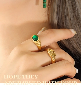 Detail of vintage gold ring with green gemstone and belt buckle style band on hand