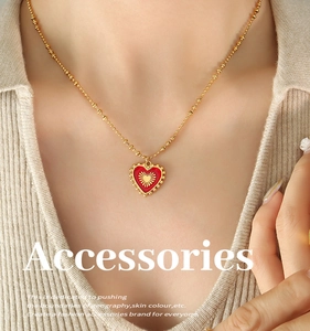 Detail of red heart pendant with sunburst pattern on golden ball chain necklace