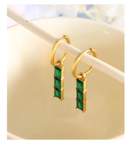 Macro detail of gold hoop earrings with three rectangular green emerald-style gemstones