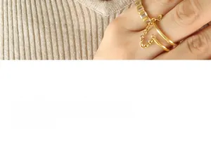 Macro shot of gold-plated rings with rectangular zircons and fine chain detail