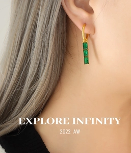 Close-up of gold hoop earring with three vertical green rectangular gemstones