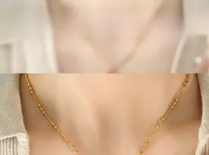 Close-up of a gold-beaded chain necklace featuring alternating large and small spheres