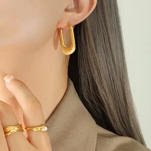 Boucles d'oreilles en U dorées à rayures et bague en perles portées par un mannequin de profil