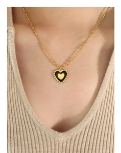 Close-up of a double-sided heart pendant necklace worn on a beige knit sweater