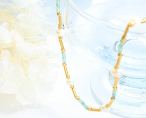 Vue macro de perles d'eau douce, d'aventurine verte et de tubes dorés sur ce collier