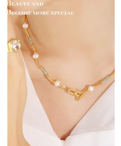 Gros plan du collier de perles avec perles vertes et boucle OT dorée sur le cou